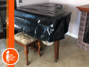 Black grand piano covered in protective cloth